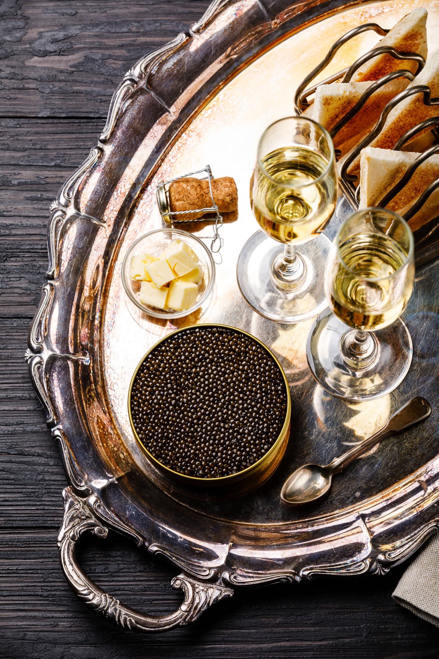 Black caviar in can, fresh bread toast and champagne on silver tray