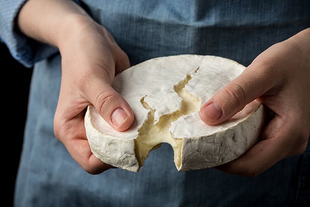 Cutting brie cheese with hands
