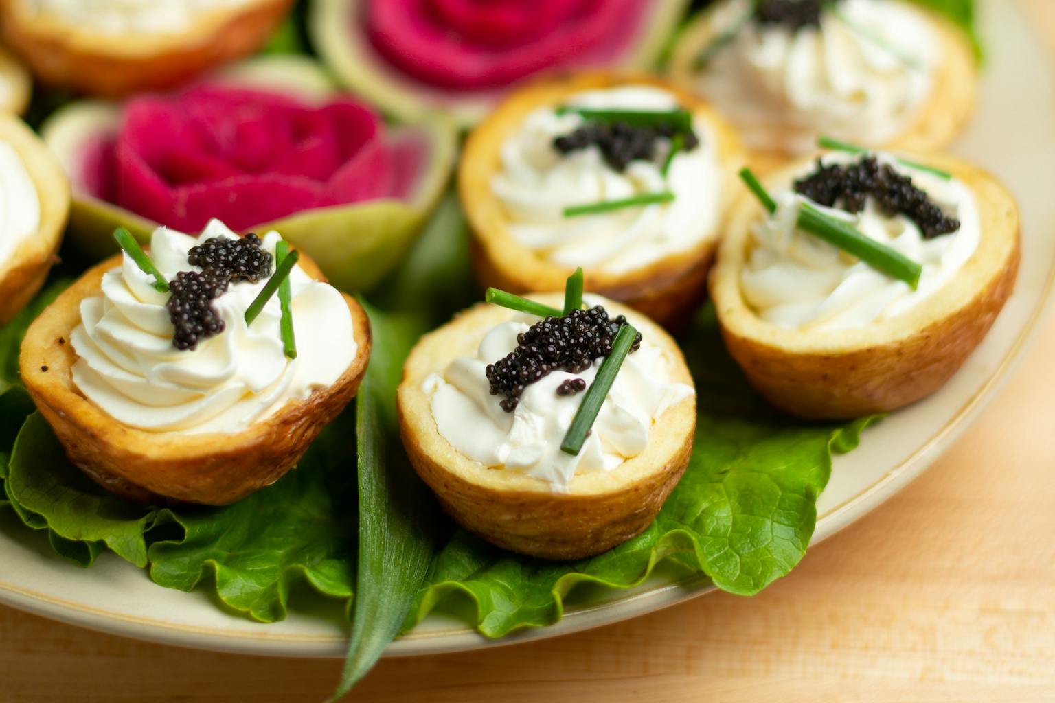 side view of mini cut potatoes with creme fraiche and caviar on top with lettuce underneath